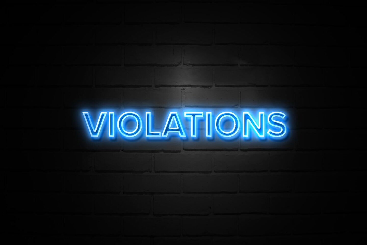Violations in neon blue Sign on black brickwall