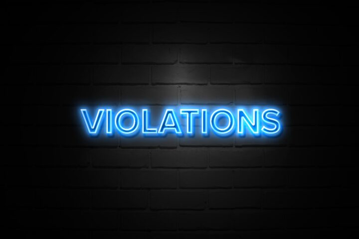 Violations in neon blue Sign on black brickwall