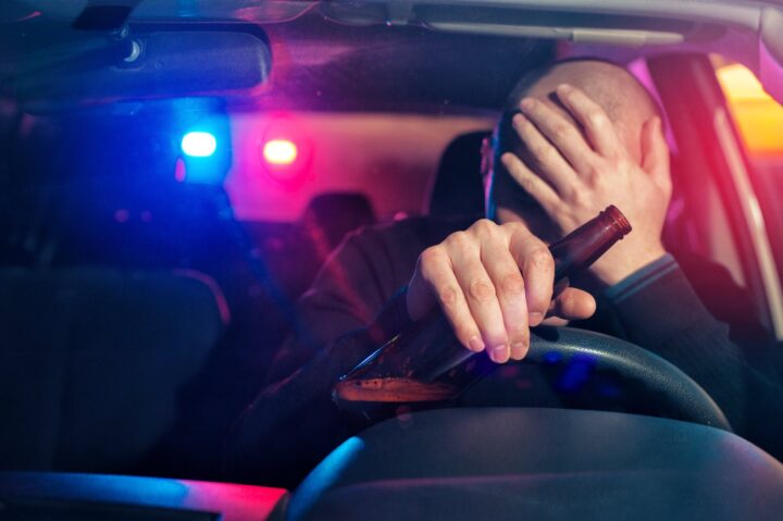 driver is caught driving under alcohol influence. Man covering his face